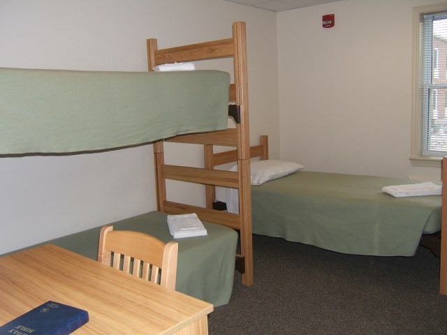 Dorm room with bunk beds and a desk