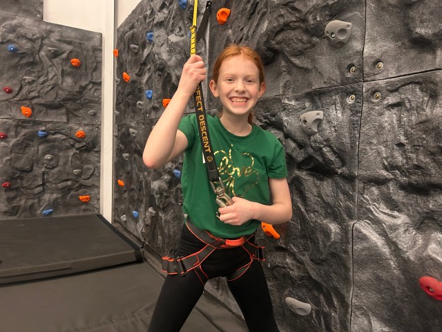 Young climber smiling on the Fieldhouse bouldering wall